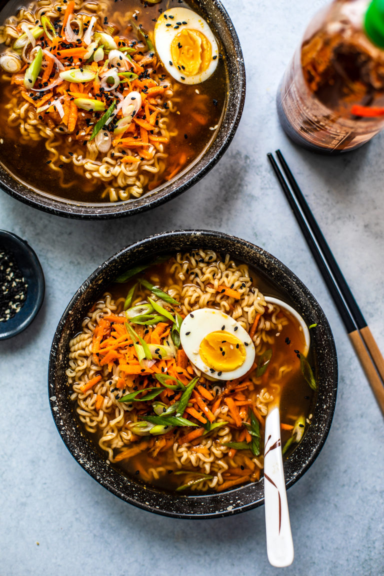 Overhead shot of two Ramen bowls and bottle of Sriracha sauce.