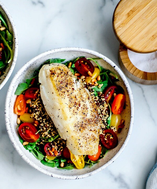 Bowl of greens and grains topped with salt and pepper crusted sea bass.