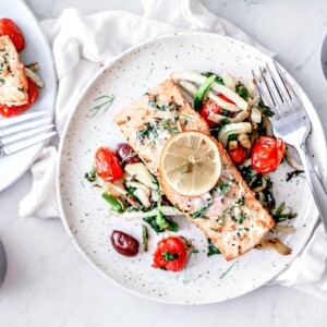 Plates of grilled salmon over salad.