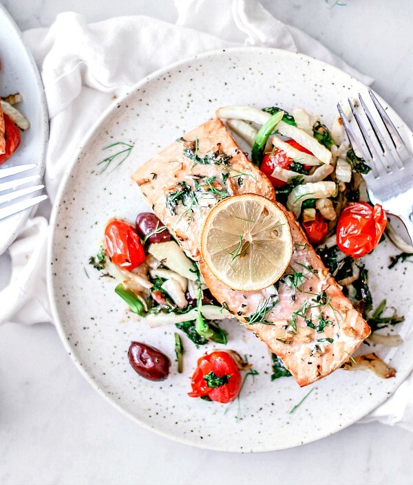 Plates of grilled salmon over salad.