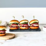 Stacked salmon sliders lined up in a row.