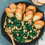 Beans and Greens in skillet lined with parmesan toasts.