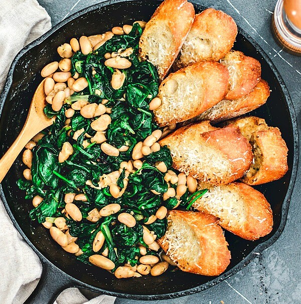 Beans and Greens in skillet lined with parmesan toasts.