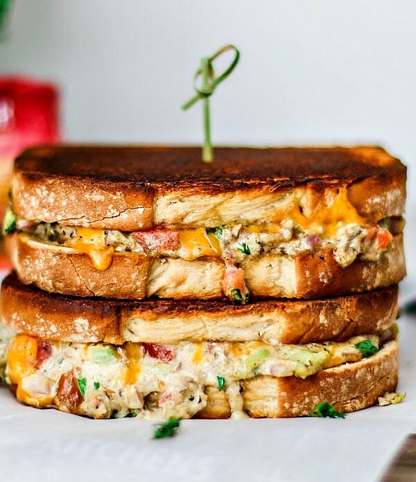 Cheddar Jalapeño Gourmet Grilled Cheese sandwiches stacked on top of one another in a melted mess.