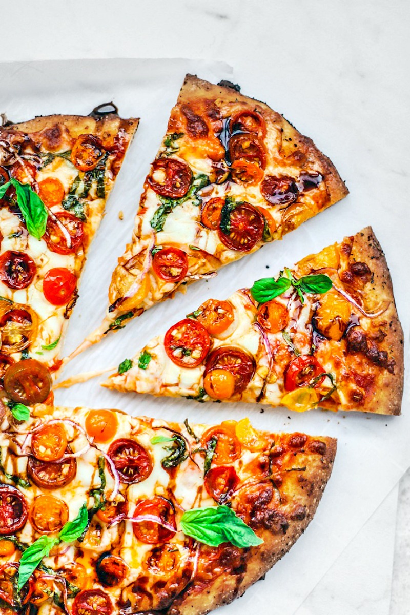 Bruschetta pizza cut into slices on a white background.