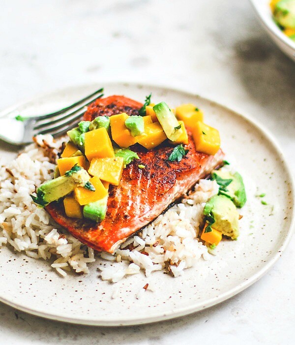 Pan-Seared Salmon on plate over rice and topped with mango and avocado salsa.