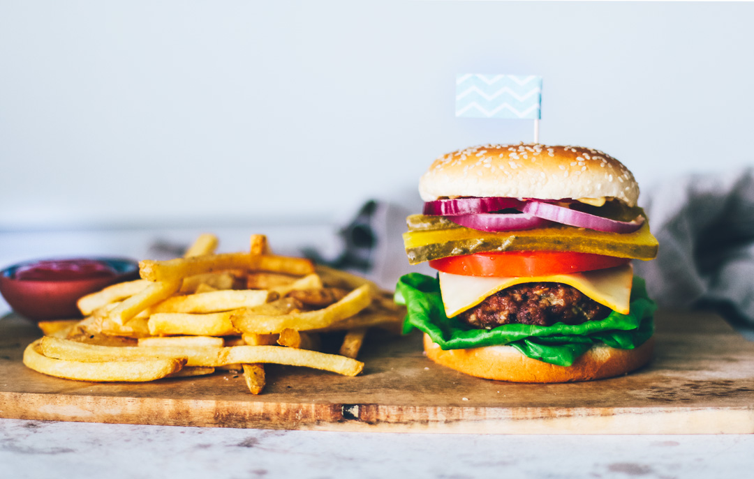 staplad nötköttburger på ett fat med pommes frites.