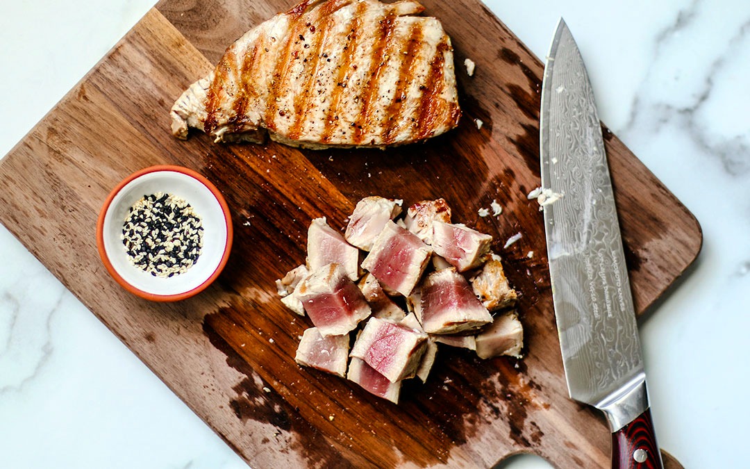 Cutting board with grilled tuna steaks on it.