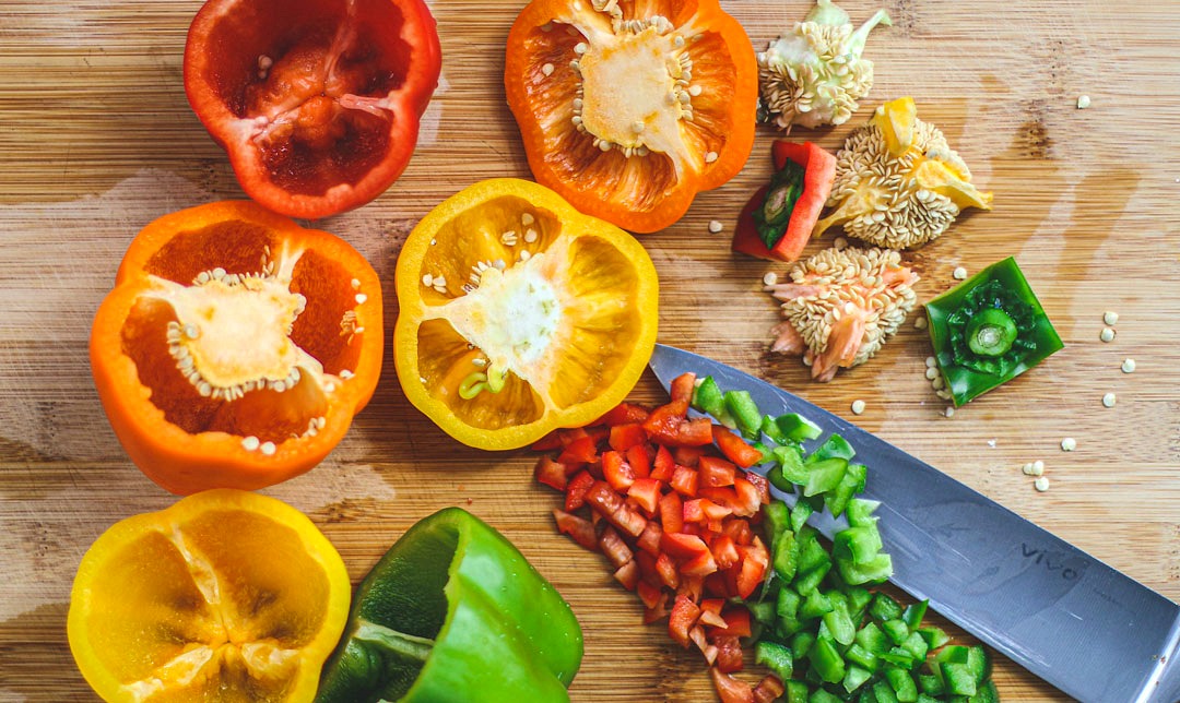 Bell peppers on a cutting board, gutted and partly chopped.