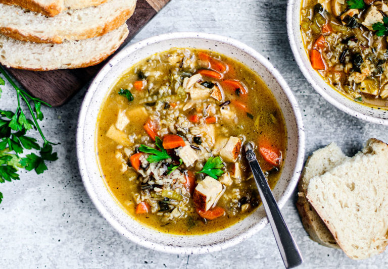 A bowl of turkey and wild rice soup with slices of fresh bread.