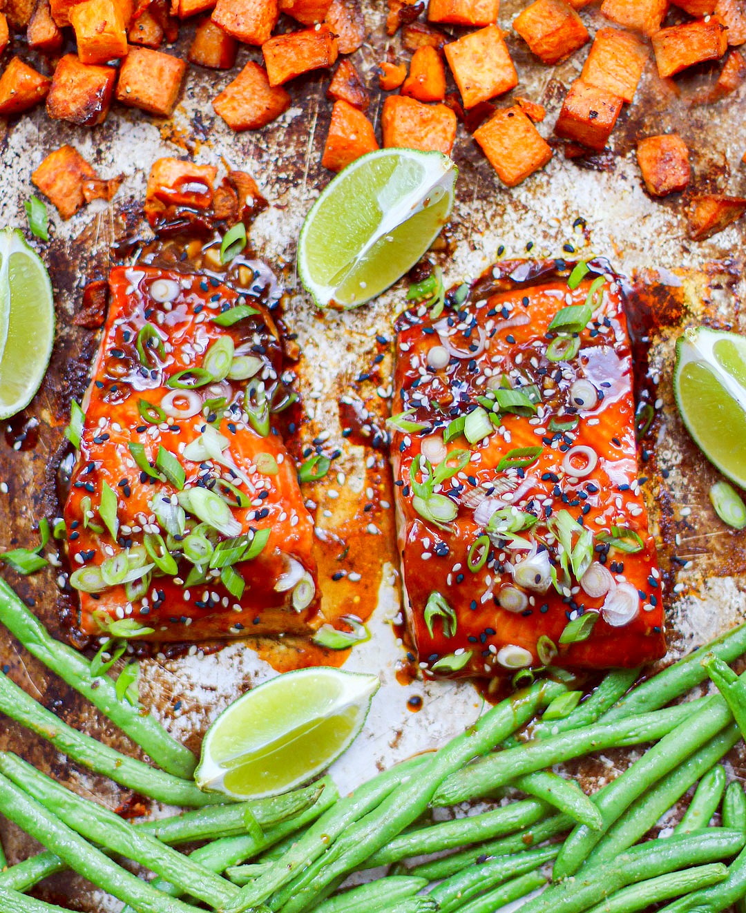 Overhead angle of two fillets of salmon on a sheet pan with veggies.