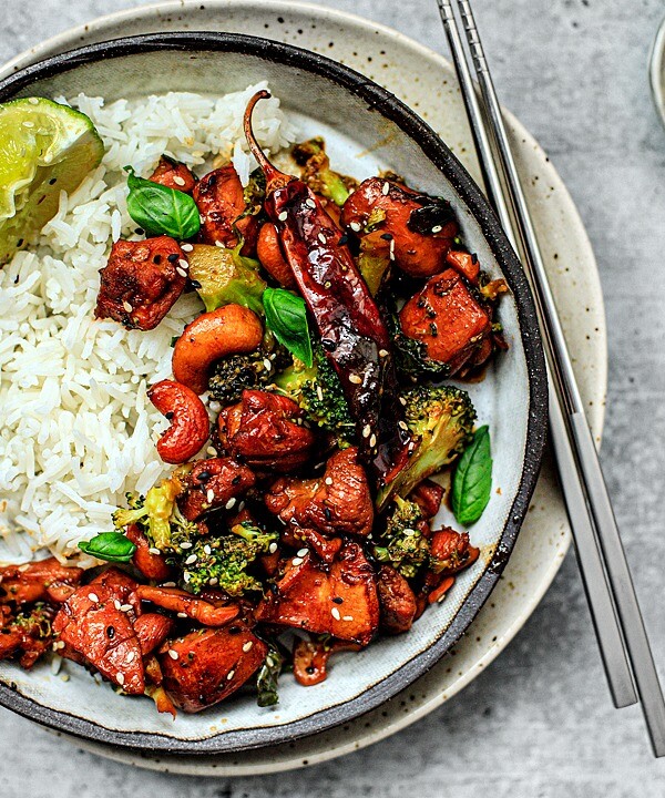 Plate of spicy sesame chicken with rice and chopsticks.