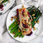 Plate of asparagus topped with salmon, fennel, blood oranges, and hazelnuts.