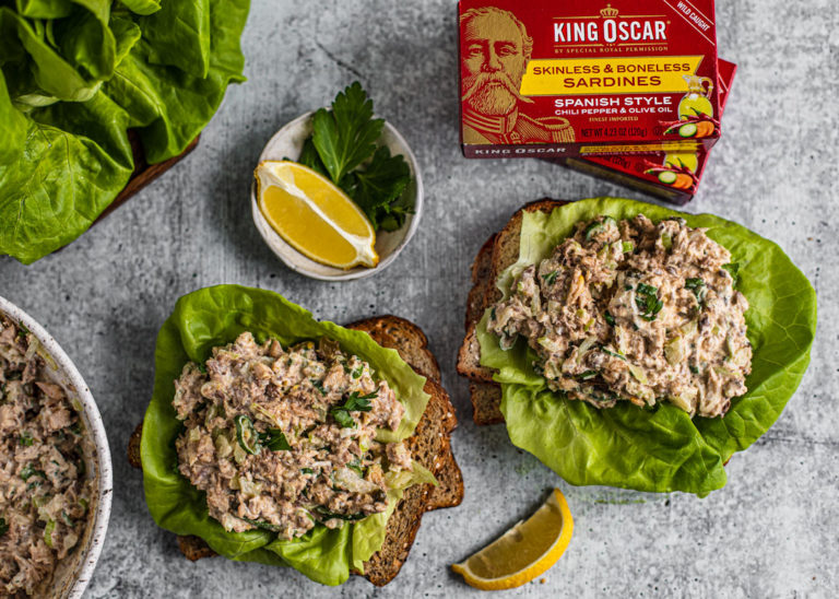 Slices of toasted bread topped with bibb lettuce and sardine salad.