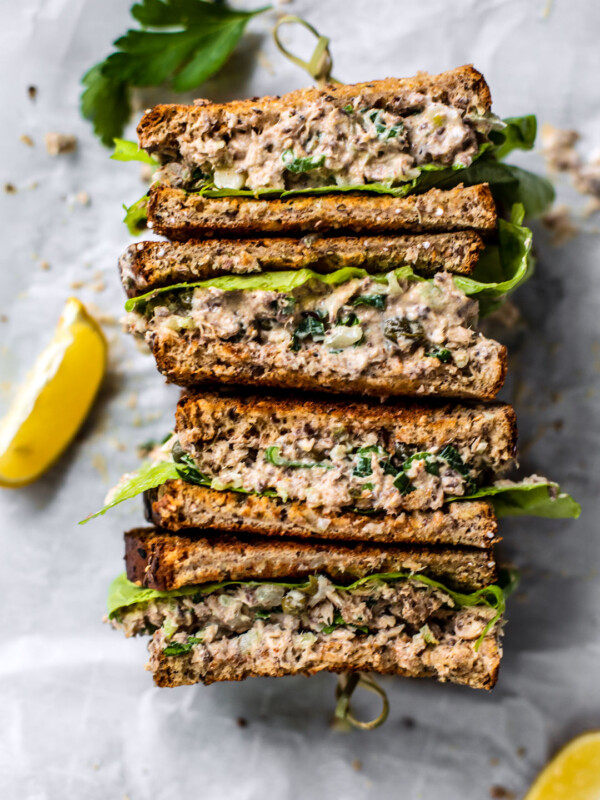 Sardine salad sandwich with lemon wedges.