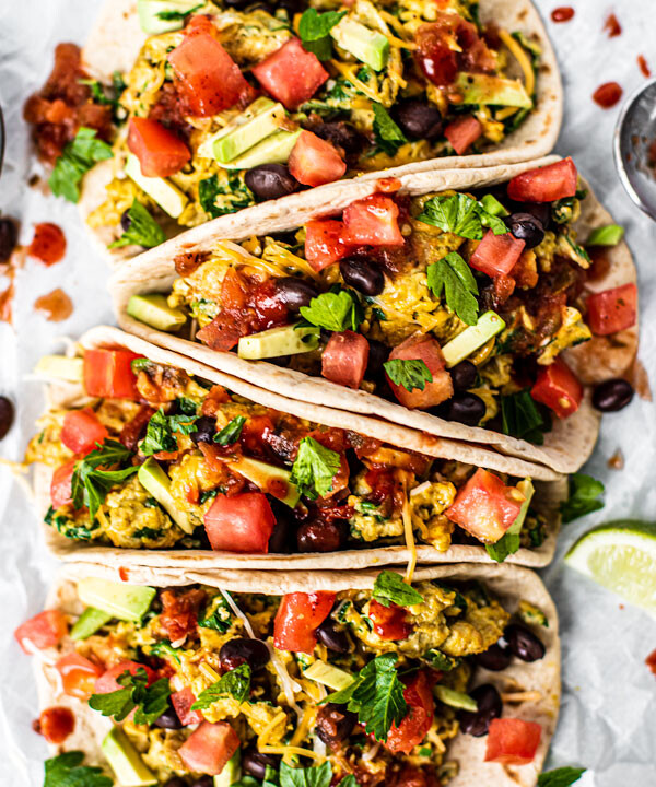 Loaded breakfast tacos full of scrambled eggs and veggies drizzled with hot sauce.