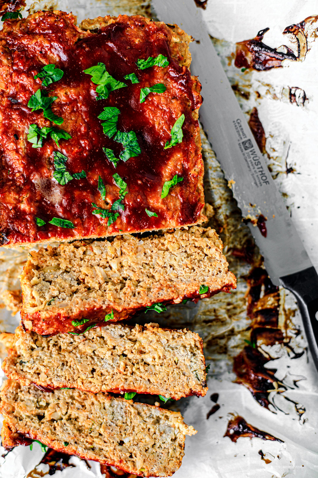 Turkey meatloaf sliced over parchment paper, garnished with parsley.