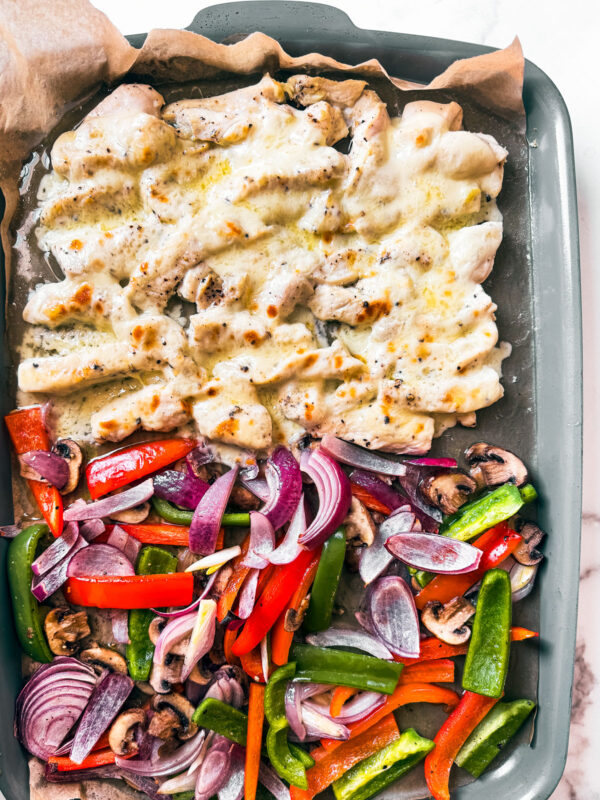 Sheet pan with veggies and cheesy chicken morsels.