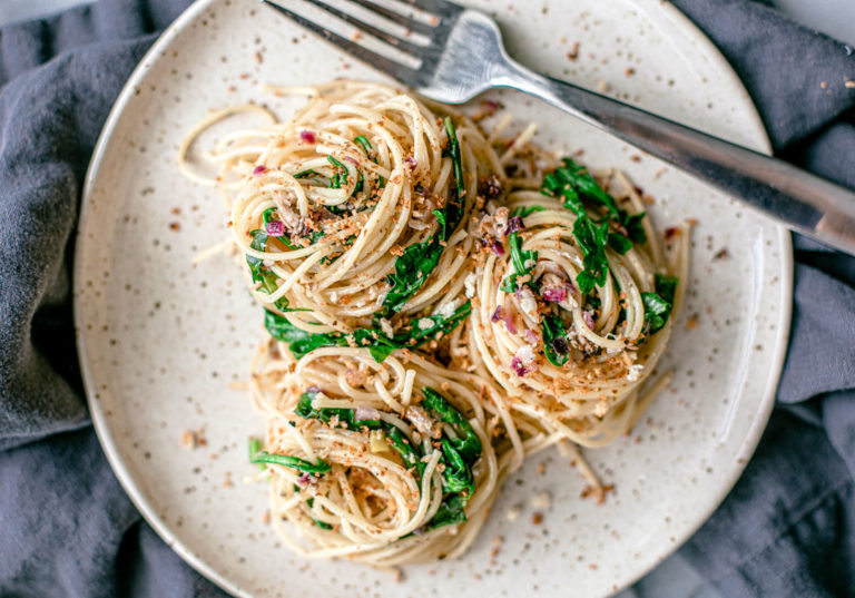 Lemon Pepper Pasta with Sardines twirled onto a plate with bright green arugula.