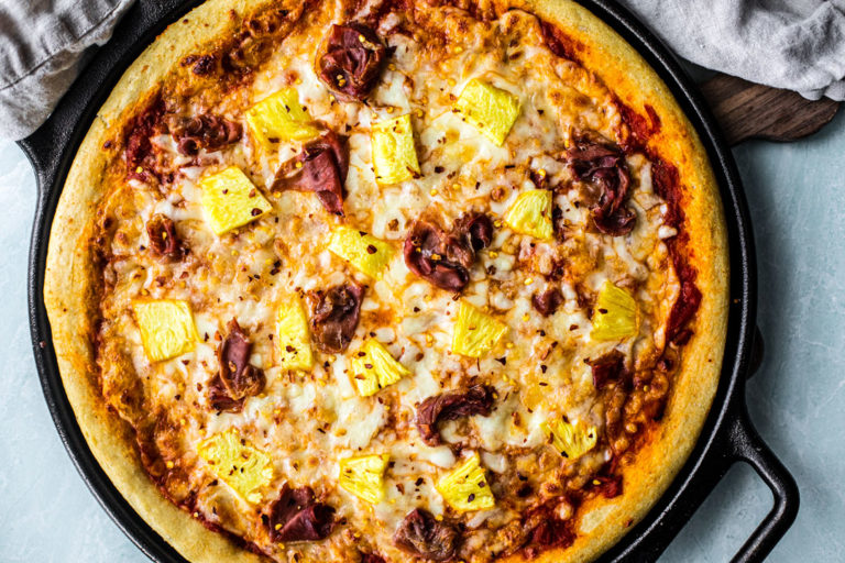 Cooked Hawaiian pizza on cast iron pizza pan.