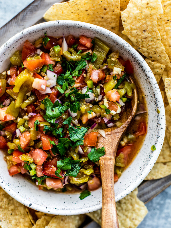 Close up of a bowl of roasted hatch chile salsa on a platter of tortilla chips.