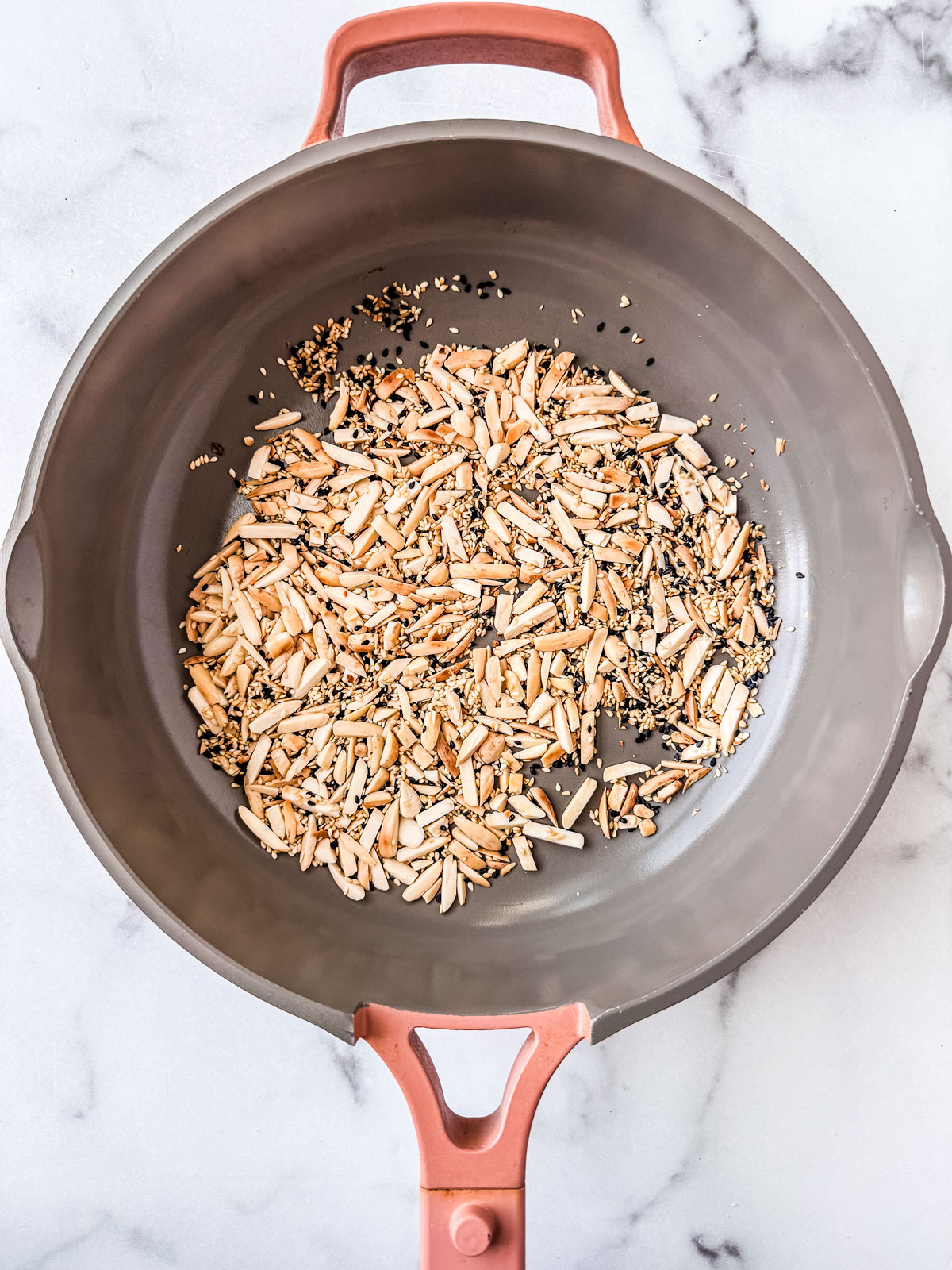 Sesame seeds and almonds toasting in a skillet.