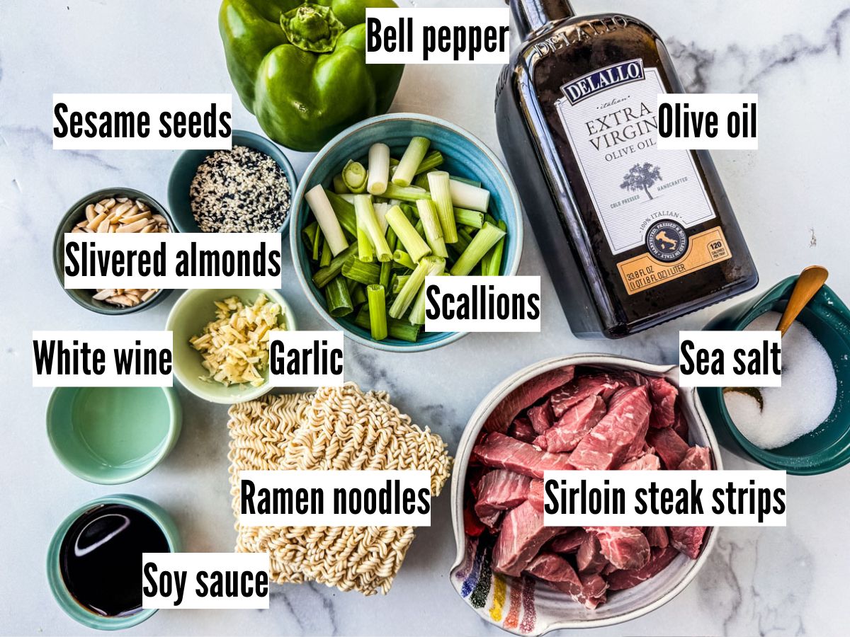 Ingredients for beef stir fry with ramen noodles on a white marble background.