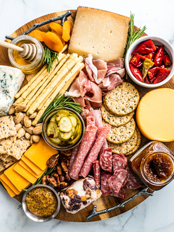 Overhead view of meat and cheese platter with nuts, fruits, jams, honey, etc.