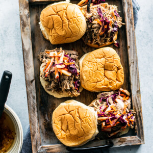 Serving tray with pulled pork sandwiches topped with apple slaw.