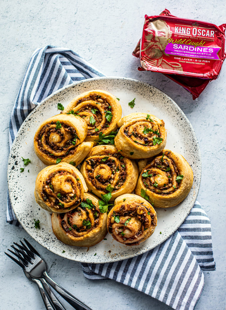 Plate full of Greek Pinwheels with cans of King Oscar sardines on the side.