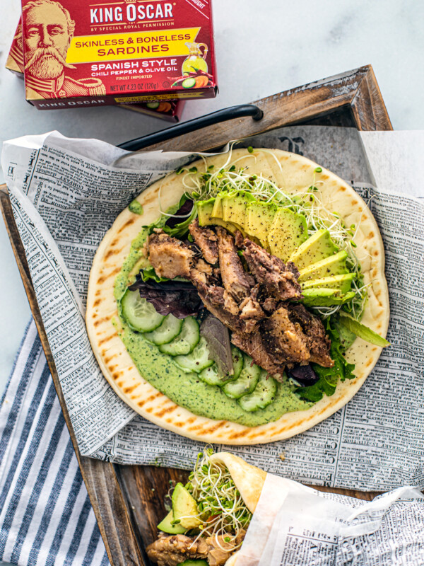 Overhead shot of pita with green goddess dressing, cucumbers, avocado, sprouts, and sardines.