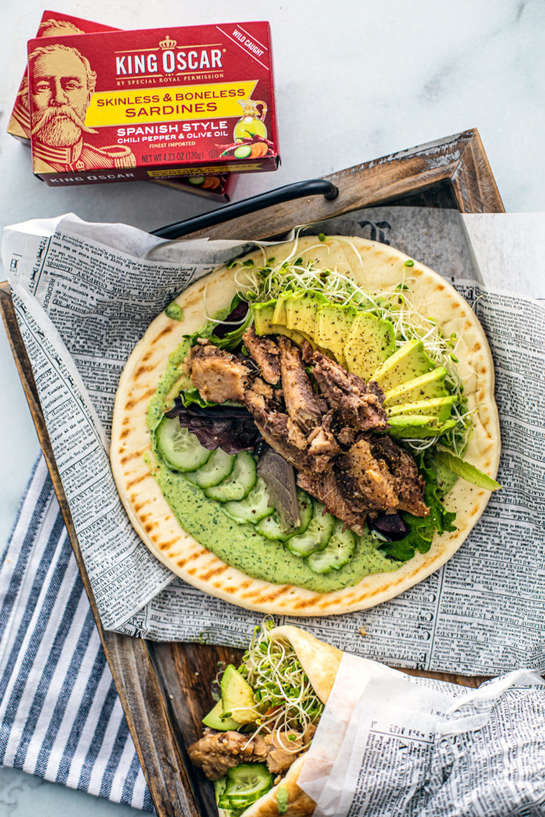 Overhead shot of pita with green goddess dressing, cucumbers, avocado, sprouts, and sardines.