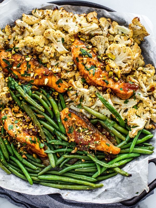 Overhead shot of sheet pan covered in green beans, cauliflower, and glazed salmon.