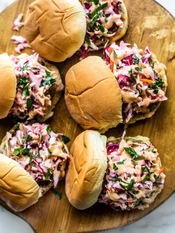 Wooden serving platter with fish sliders topped with slaw.