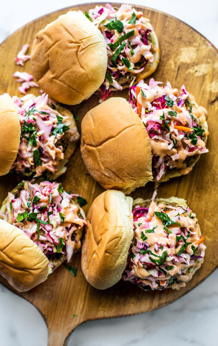 Wooden serving platter with fish sliders topped with slaw.