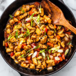 Skillet full of sweet and sour chicken with peppers and onions.