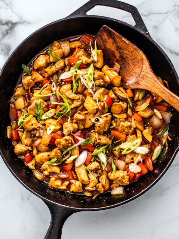 Skillet full of sweet and sour chicken with peppers and onions.
