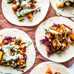 A flatlay of colorful fish tacos, some drizzled with jalapeno sauce.