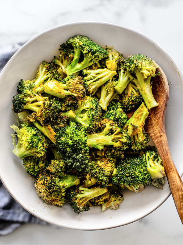 White serving bowl full of cooked broccoli florets.