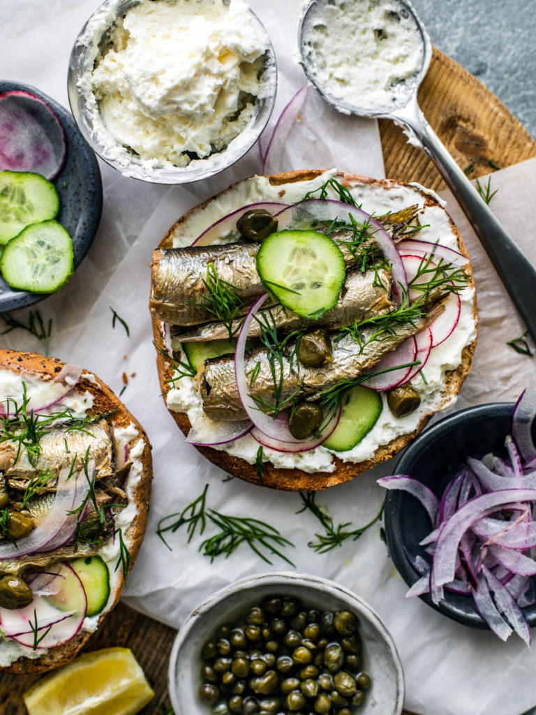 Close up of bagel with cream cheese and sardines.