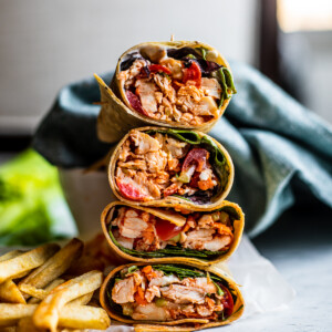 Buffalo wrap halves stacked on top of one another with a side if fries.