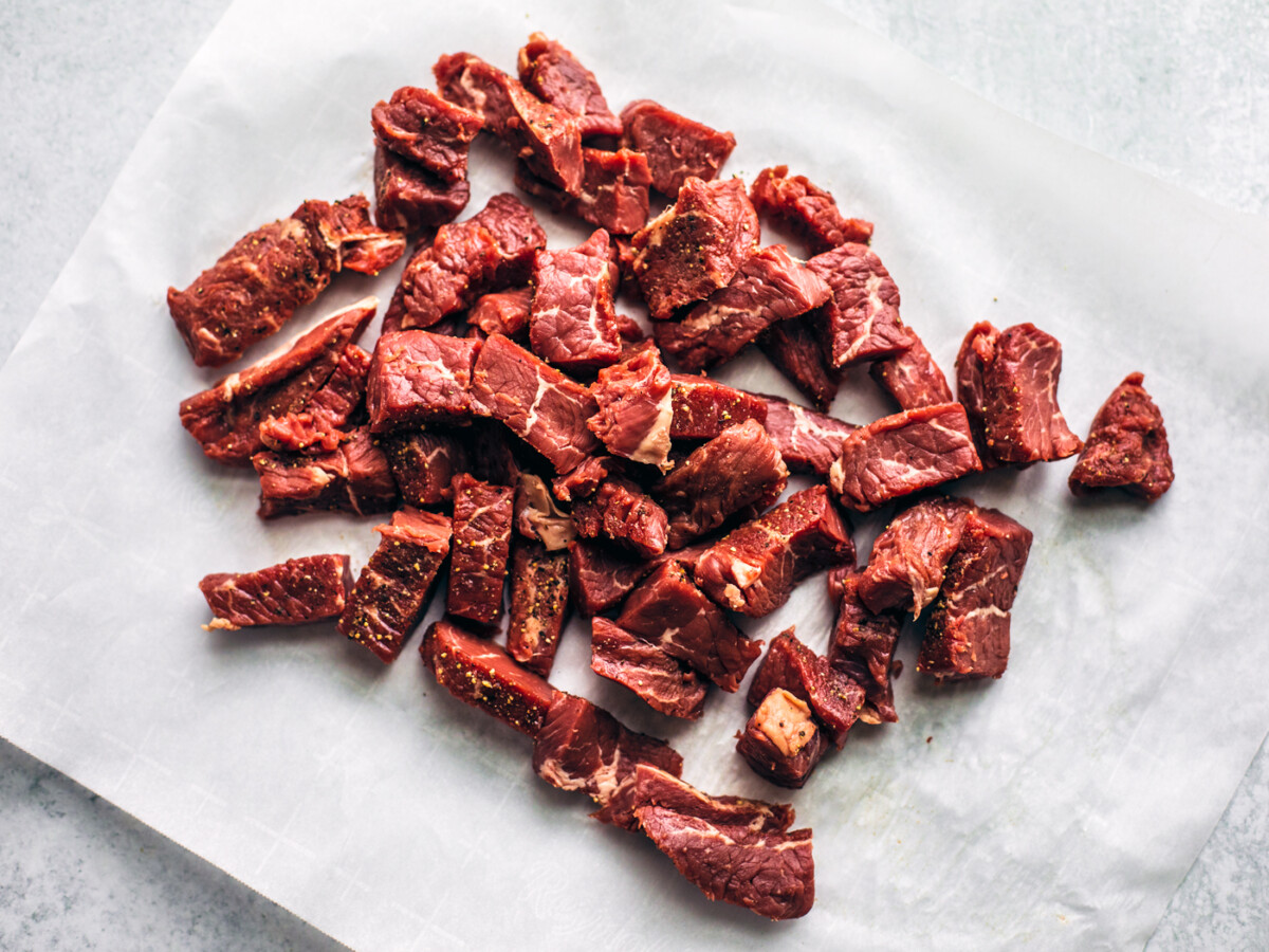 Raw steak bites on parchment paper.