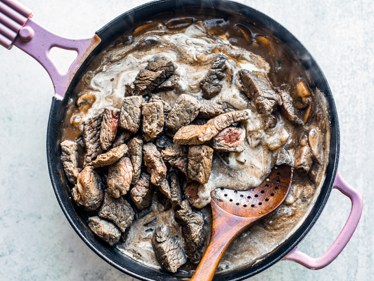 Beef bites being tossed into the sour cream and gravy.