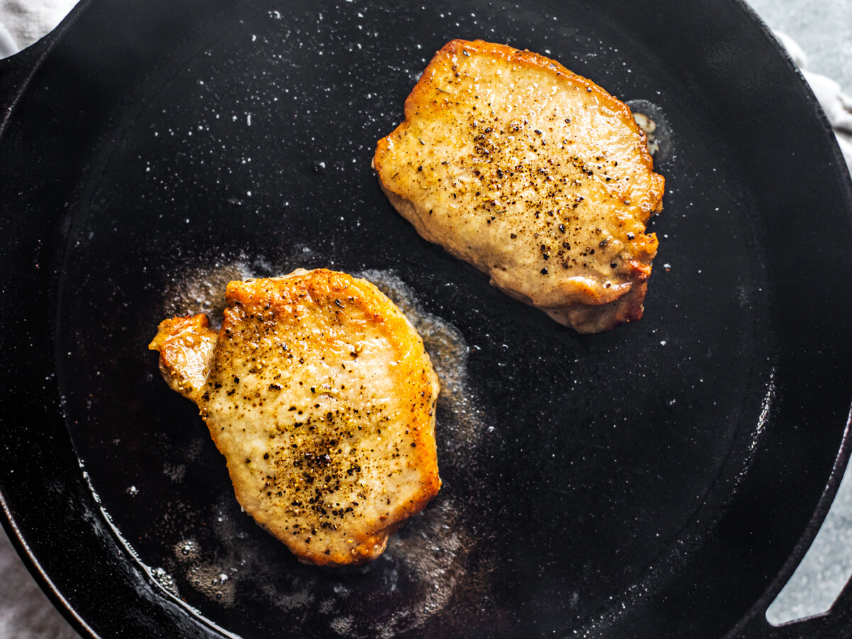 Golden pork chops in a cast iron skillet.