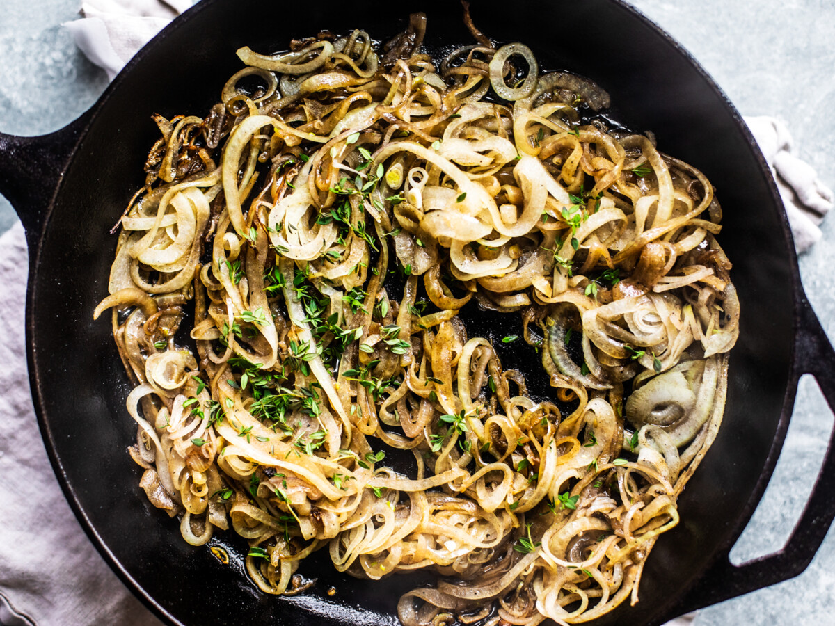 Cast iron skillet full of onions and thyme.