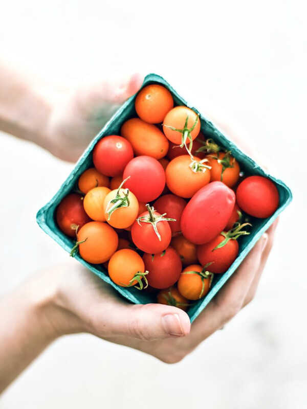 Hands holding small carton of cherry tomatoes