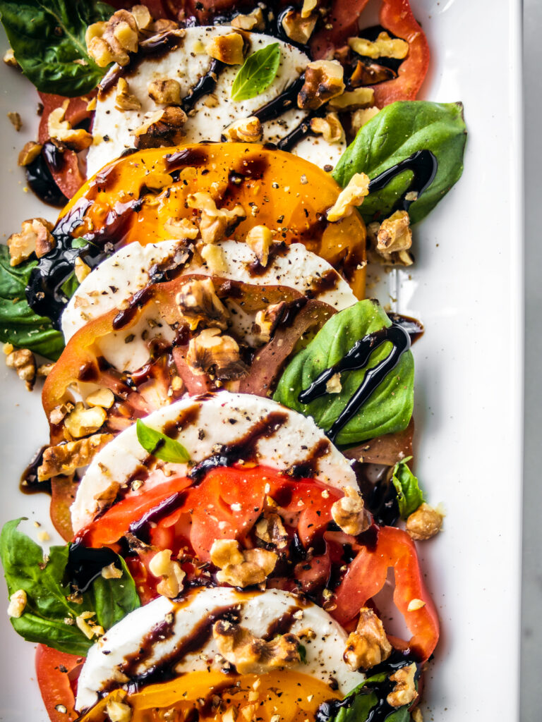 Close up of tomatoes, mozzarella, and basil drizzled with balsamic glaze.