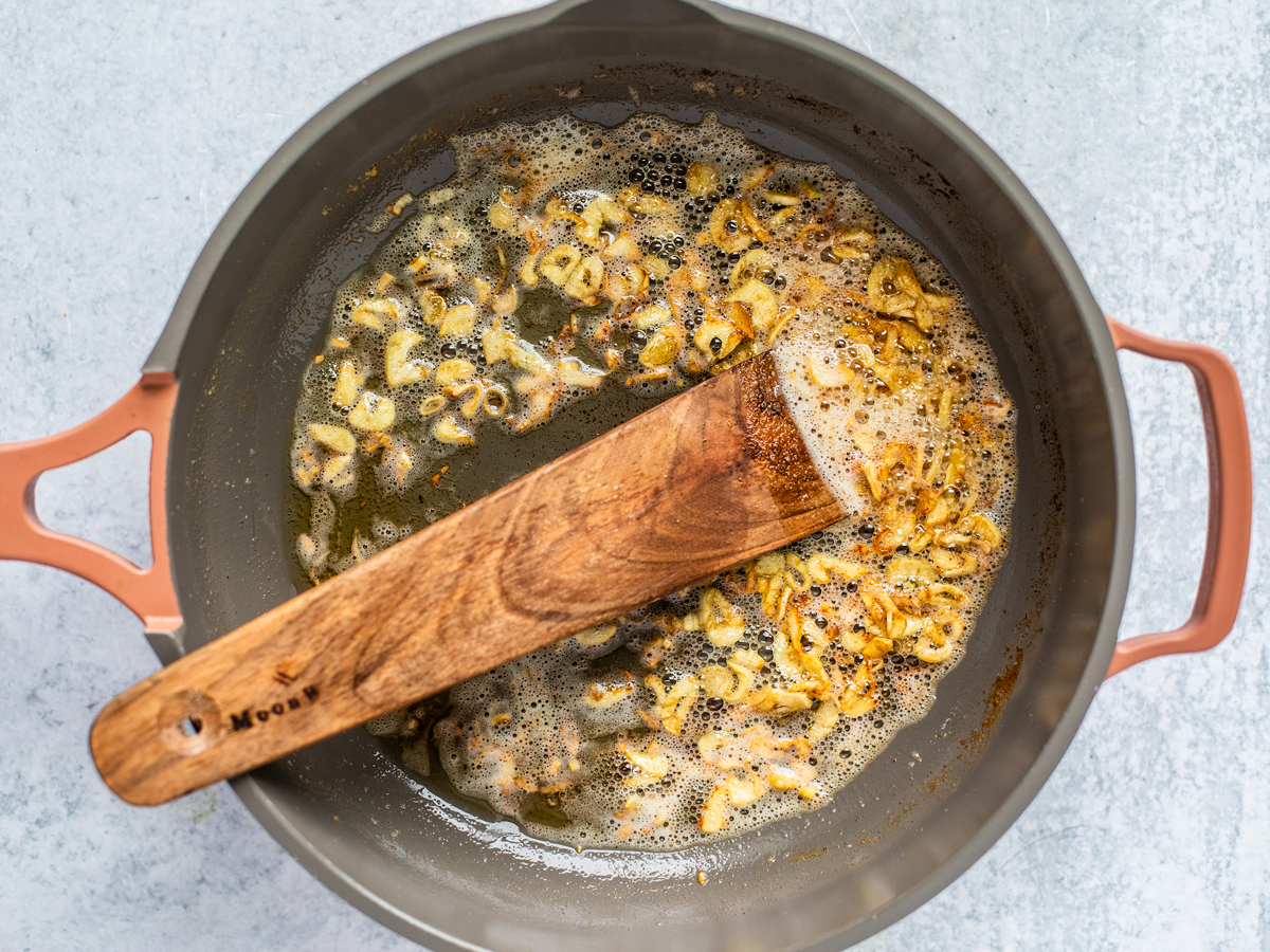 Skillet full of garlic slices in butter.