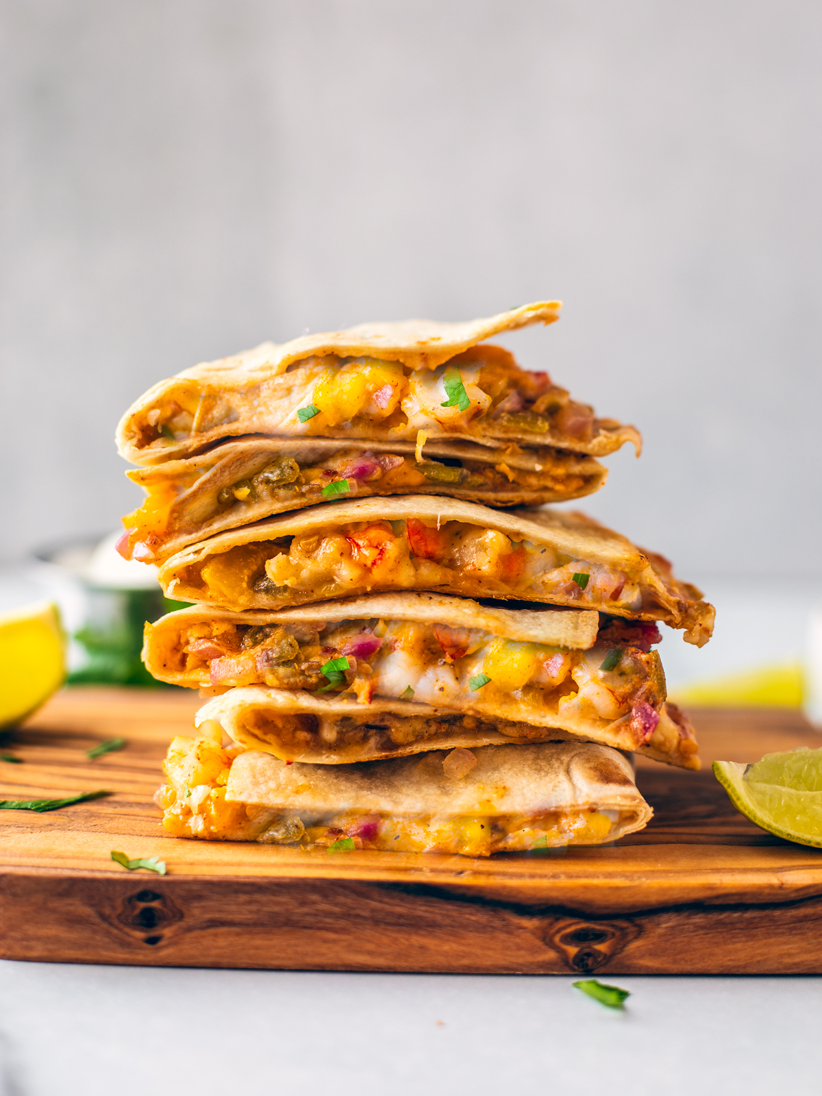 Shrimp fajita wedges stacked on top of one another on a wooden serving board.