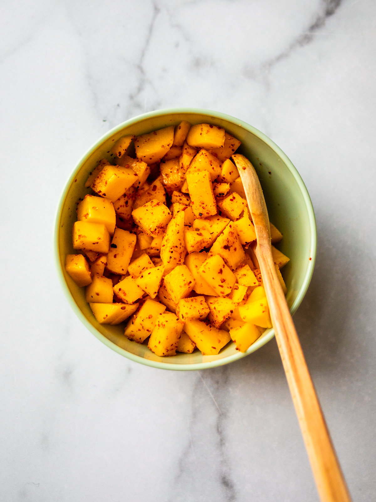 Small mixing bowl of Tajin-seasoned mango cubes.